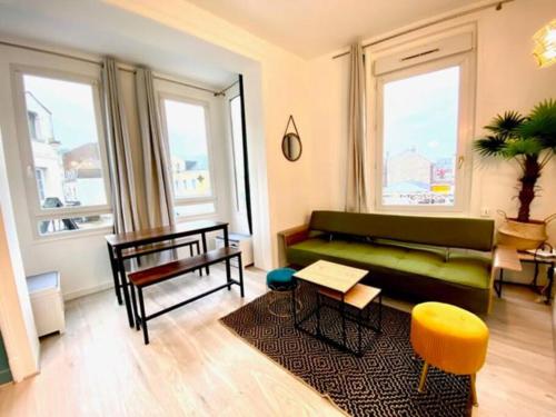 a living room with a green couch and some windows at Etretat au Coeur in Étretat
