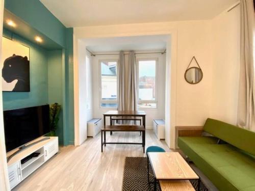 un salon avec un canapé vert et une télévision dans l'établissement Etretat au Coeur, à Étretat