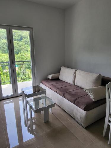un soggiorno con divano e tavolo in vetro di Novi Relax apartment a Herceg-Novi