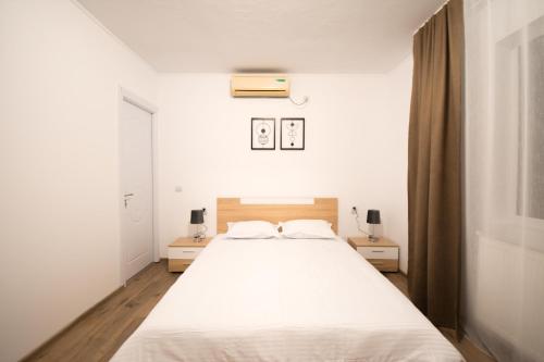 1 dormitorio con 1 cama blanca y 2 mesitas de noche en Casa Calina en Călimăneşti