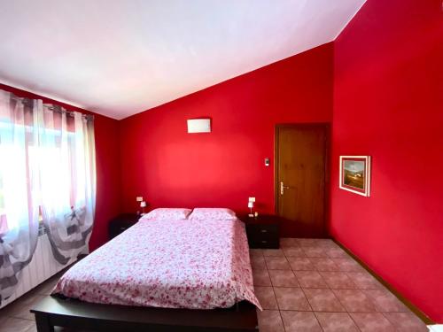 1 dormitorio con una pared roja y 1 cama en Casa Fanny, en Castelnuovo del Garda