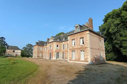 uma antiga casa de tijolos com um grande quintal em Château de Heuqueville em Heuqueville