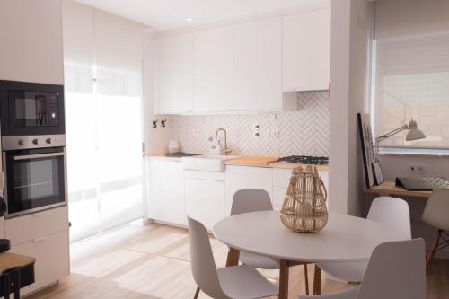 a kitchen with white cabinets and a table and chairs at Apartamento Praia Buarcos in Figueira da Foz