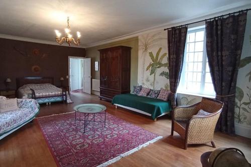 a living room with a bed and a couch and a table at Château de Heuqueville in Heuqueville