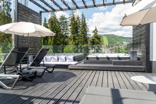 a deck with chairs and a couch and an umbrella at Bukville Hotel & SPA in Bukovel