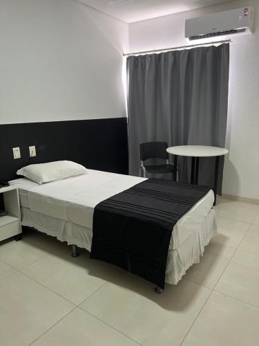 a bedroom with a bed and a table and a window at Hotel São Vicente in Araguaína