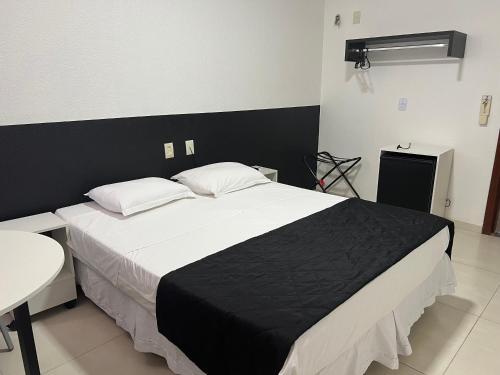 a bedroom with a black and white bed and a table at Hotel São Vicente in Araguaína