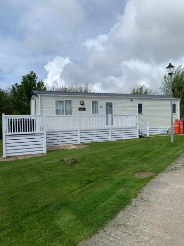 a white house with a white fence in a yard at Meadows 3 NEW BEACH HOLIDAY PARK in Dymchurch