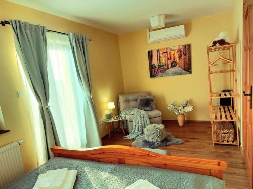 ein Schlafzimmer mit einem Bett, einem Stuhl und einem Fenster in der Unterkunft Linczi Ház in Csopak