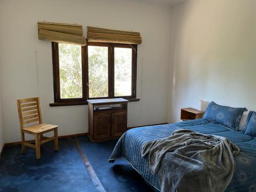 Los MollesにあるCon vista a las sierras, Villa Las Rosas, Traslasierras, Cordobaのベッドと椅子と窓のある寝室