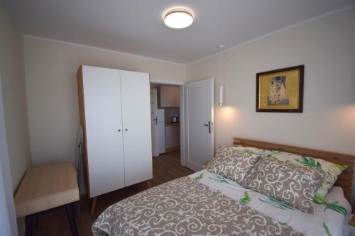 a bedroom with a bed and a white cabinet at Apartamenty Morze Plażowa 4A i 4B in Sarbinowo