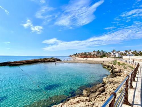 a beach with a fence next to the water at Olive Tree Bungalow La Zenia in Orihuela Costa