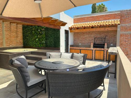 eine Terrasse mit einem Tisch, Stühlen und einem Grill in der Unterkunft Doña Jose Suite & Apartments in San Miguel de Allende