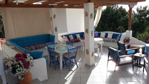 eine Terrasse mit blauen Sofas sowie einem Tisch und Stühlen in der Unterkunft Kocheilas Studios in Gialiskari