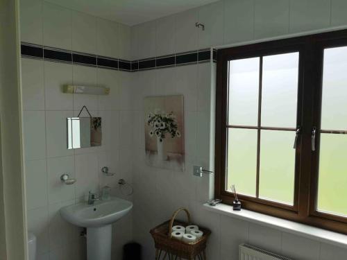baño blanco con lavabo y ventana en Lakeside House in Drumshanbo, en Drumshanbo