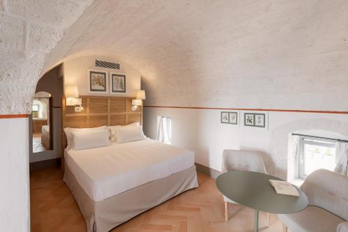 ein Schlafzimmer mit einem Bett und einem Tisch in einem Zimmer in der Unterkunft Masseria Auraterrae in Polignano a Mare