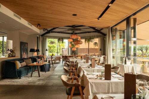 ein Restaurant mit weißen Tischen, Stühlen und Fenstern in der Unterkunft Hotel Muchele in Meran