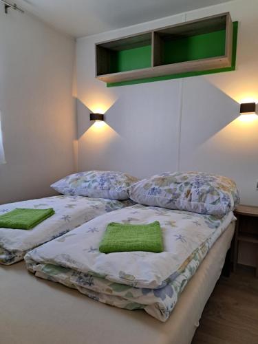 two beds in a room with two green pillows at Mobilheim / Chalet in Seekirchen am Wallersee