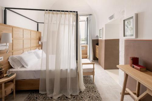 1 dormitorio con 1 cama con cortina blanca en Masseria Auraterrae, en Polignano a Mare