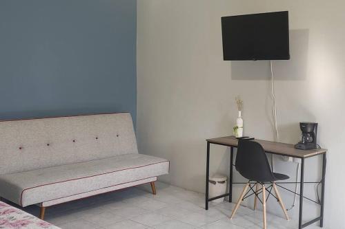 a bedroom with a couch and a desk with a television at Casa Inés/ Terraza/ Centro de Oaxaca in Oaxaca City