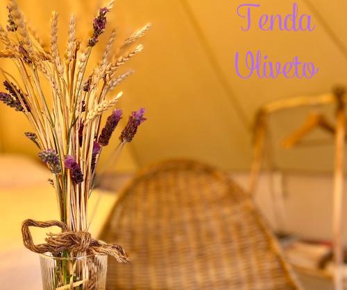 a vase with purple flowers sitting on a table with a chair at Stecadó Glamping in Dolceacqua