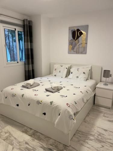 a bedroom with a white bed with a white comforter at Jardines Apartment in Sitio de Calahonda