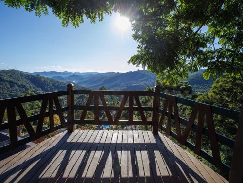 um banco de madeira com vista para as montanhas em Pousada Varanda das Colinas em Monte Verde