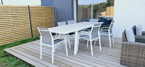 une table et des chaises blanches sur une terrasse dans l'établissement Sur la route des plages, à Saint-Philibert