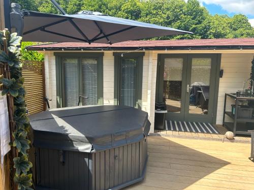 une maison avec un parasol sur une terrasse dans l'établissement Beauslodge Authentic Log Cabin With Private Hot Tub, à Arford