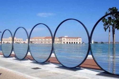 a row of metal hoops in front of a body of water at Helena's house in Ermoupoli