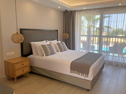 a bedroom with a large bed and a large window at Anassa Resort Halkidiki - Adults only in Kalivia Poligirou