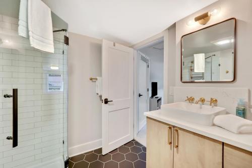 ein weißes Badezimmer mit einem Waschbecken und einem Spiegel in der Unterkunft Cherry Street Cottage in Boyne City