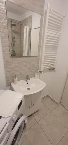 een witte badkamer met een wastafel en een spiegel bij Joy Apartments in Mangalia