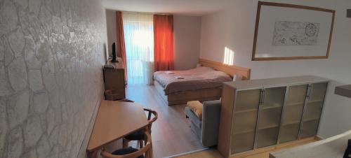 ein kleines Schlafzimmer mit einem Bett, einem Schreibtisch und einem Tisch in der Unterkunft Gréti Apartman in Zalakaros