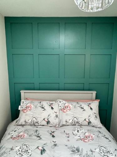 a bedroom with a green wall and a bed with two pillows at Blue Haven in Moville