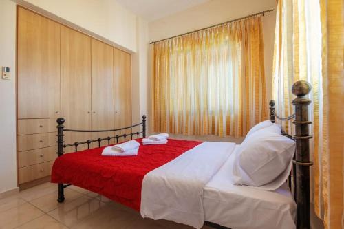 1 dormitorio con 1 cama con sábanas rojas y almohadas blancas en Valerios & Maria, en Gerani