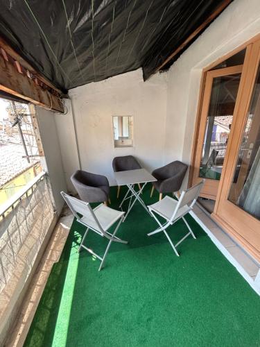 une table et des chaises sur un balcon avec un sol vert dans l'établissement Charmant Appartement 2 ch Nyons-centre ville, à Nyons