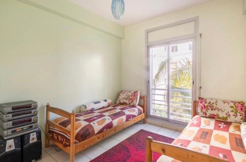 1 Schlafzimmer mit 2 Betten und einem Fenster in der Unterkunft Appartement confortable residence koutoubia quartier nassim casablanca in Casablanca