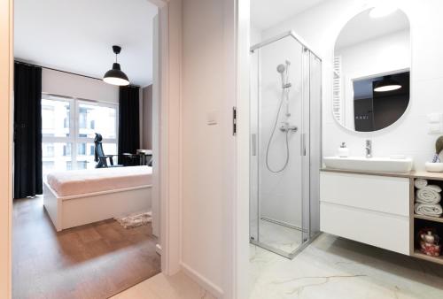 a white bathroom with a shower and a sink at Nowohucka Apartament in Krakow