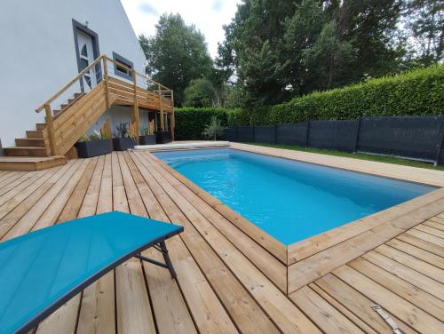 einen Pool auf einer Holzterrasse mit einem blauen Tisch in der Unterkunft Ty Breizh jet in Ergué-Gabéric