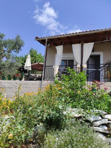 uma casa com cortinas brancas num jardim em Traditional villa Palio em PalaiónTsiflíkion