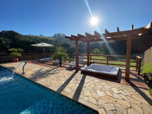 a swimming pool with a wooden pergola and a swimming pool at CHÁCARA COM PISCINA CLIMATIZADA e JACUZZI in Socorro