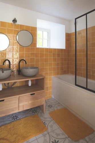 a bathroom with two sinks and a tub and a mirror at Escale de Gerbold in Gratot