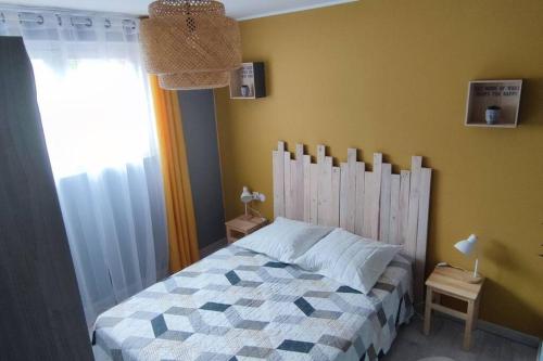 een slaapkamer met een bed met een houten hoofdeinde en een raam bij Appartement cosy sur Agde pour 4 personnes maxi. in Agde