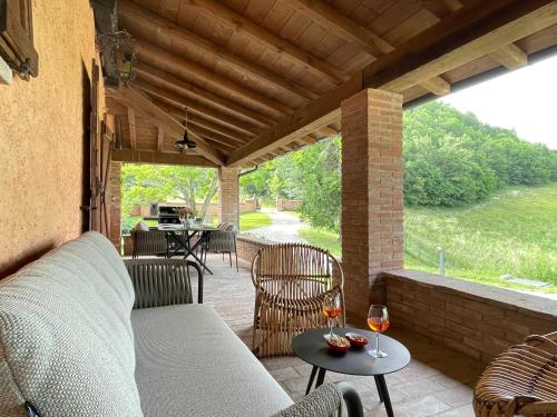 Val di Codena - Holiday Home في Vetto: فناء مع أريكة وطاولة مع كؤوس النبيذ