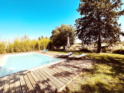 - une piscine avec deux bancs à côté d'une terrasse en bois dans l'établissement Magnifique Loft - Piscine - Tennis - Babyfoot, à Nîmes