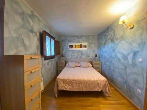 1 dormitorio con cama y pared azul en Duplex Altos de Santiago Jardin en Villanúa