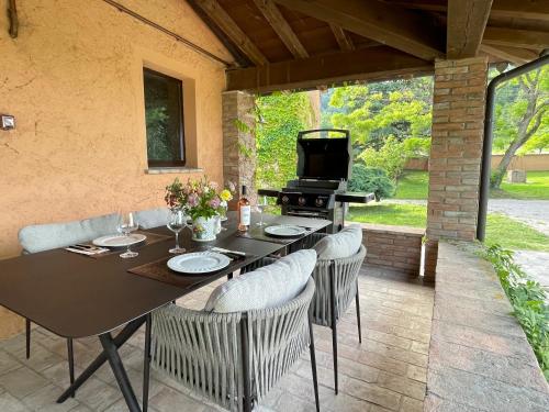 a patio with a table and chairs and a grill at Val di Codena - Holiday Home in Vetto
