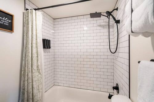 y baño con ducha de azulejos blancos y cortina de ducha. en Lady Madonna Sage Flat en Salt Lake City