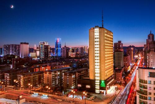 un perfil urbano por la noche con un edificio alto en Holiday Inn Taiyuan City Center en Taiyuán